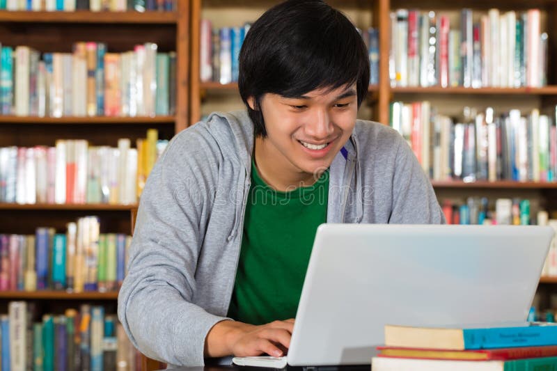 Aziatische mens in bibliotheek met laptop stock foto Aziatische mens in bibliotheek met laptop stock foto