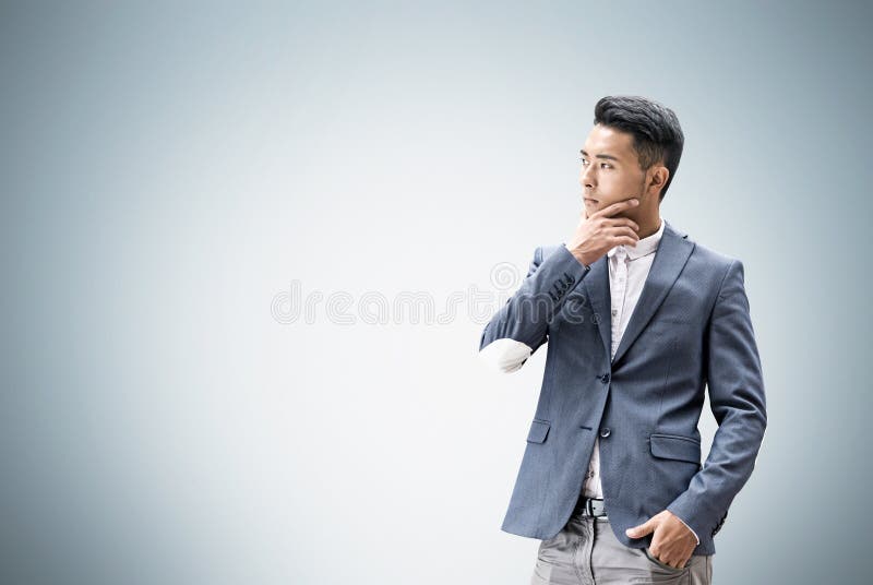Aziatische mens die dichtbij grijze muur denken royalty-vrije stock fotografie Aziatische mens die dichtbij grijze muur denken royalty-vrije stock fotografie
