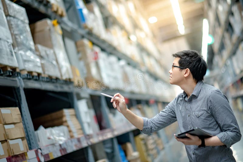 Aziatische mens die inventarisatie doen door tablet in pakhuis te gebruiken royalty-vrije stock fotografie Aziatische mens die inventarisatie doen door tablet in pakhuis te gebruiken royalty-vrije stock fotografie