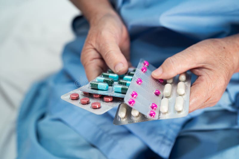 Aziatische oudere of oudere vrouwelijke patiënte die antibiotica vasthoudt capsule pillen in blisterverpakking voor behandeling in stock afbeeldingen Aziatische oudere of oudere vrouwelijke patiënte die antibiotica vasthoudt capsule pillen in blisterverpakking voor behandeling in stock afbeeldingen