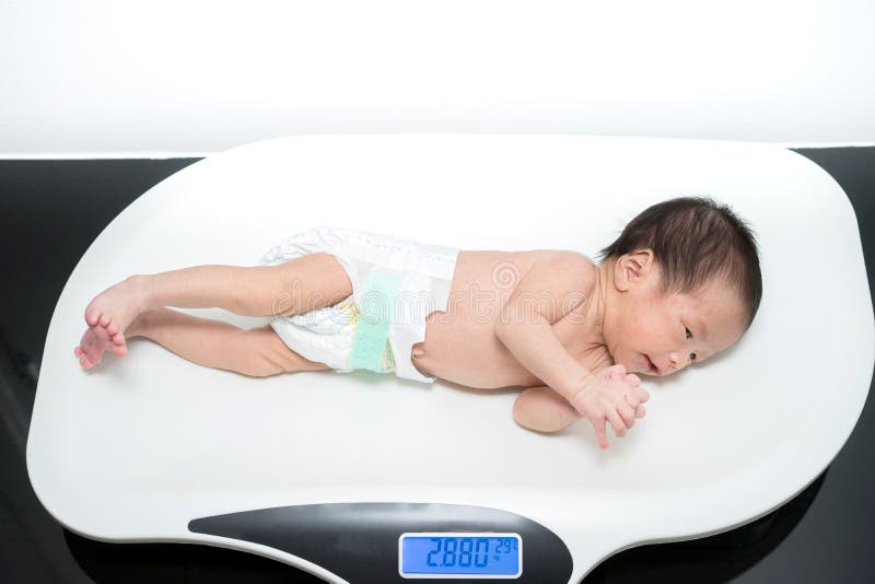 Aziatische pasgeboren baby die op de schalen leggen