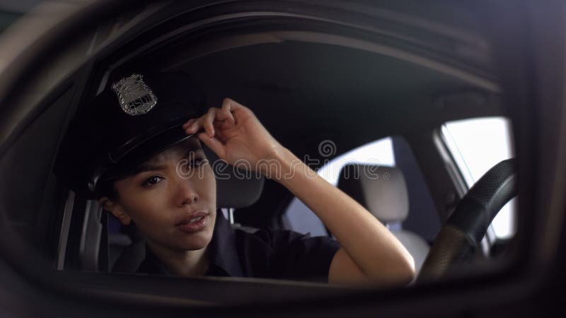 Aziatische politieman die haar eenvormig GLB aanpassen die achteruitkijkspiegel onderzoeken royalty-vrije stock foto's Aziatische politieman die haar eenvormig GLB aanpassen die achteruitkijkspiegel onderzoeken royalty-vrije stock foto's
