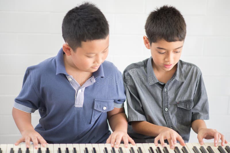 Asian student boys playing piano together in the class. Asian student boys playing piano together in the class