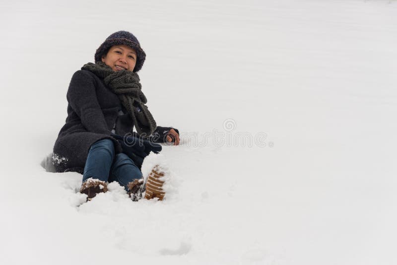 Aziatische vrouw die in hoed in sneeuw leggen stock foto Aziatische vrouw die in hoed in sneeuw leggen stock foto