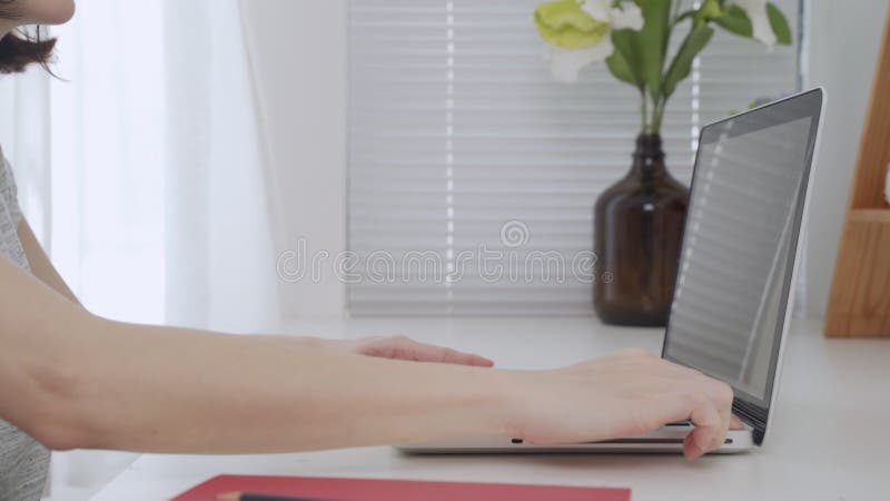 Aziatische vrouw opent computerlaptop en zet de werktafel in de buurt van het venster thuis aan.