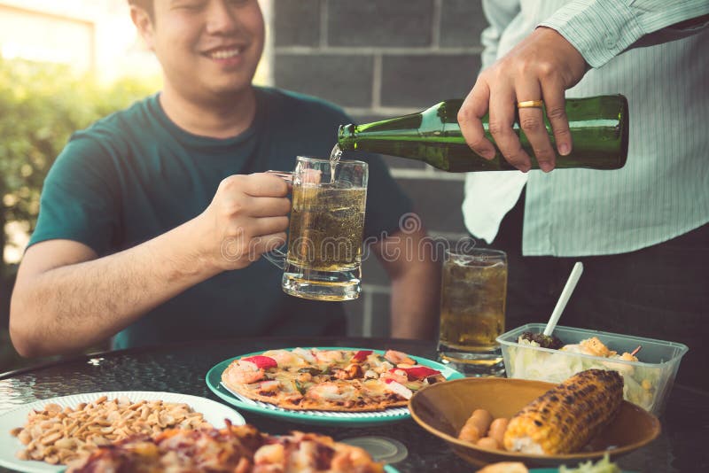 Azjatyccy przyjaciele pomagaj? nalewa? piwo w butelk? jego partner wp?lnie i mie? zabaw? w ?wi?towaniu fotografia stock Azjatyccy przyjaciele pomagaj? nalewa? piwo w butelk? jego partner wp?lnie i mie? zabaw? w ?wi?towaniu fotografia stock