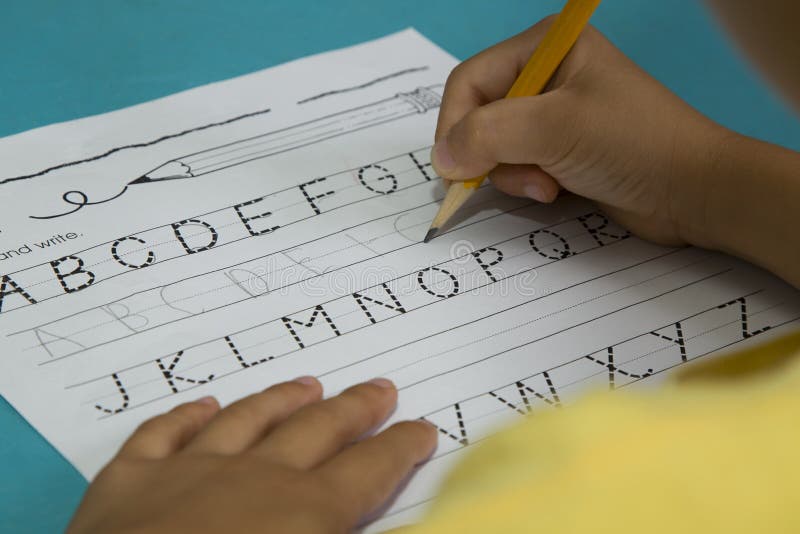 Azjatycka chłopiec pisze listowym G z żółtym ołówkiem