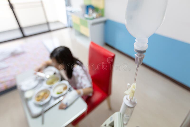 Azjatycka dziewczynka jest na kroplówce otrzymując roztwór soli, taca ze śniadaniem, pacjentka jedząca jedzenie w pokoju szpitala zdjęcie stock Azjatycka dziewczynka jest na kroplówce otrzymując roztwór soli, taca ze śniadaniem, pacjentka jedząca jedzenie w pokoju szpitala zdjęcie stock