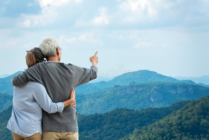 Azjatycka para w stylu życia przytulająca się i wskazująca na górską naturę Starzy ludzie szczęśliwi w miłości romantycznej i odp