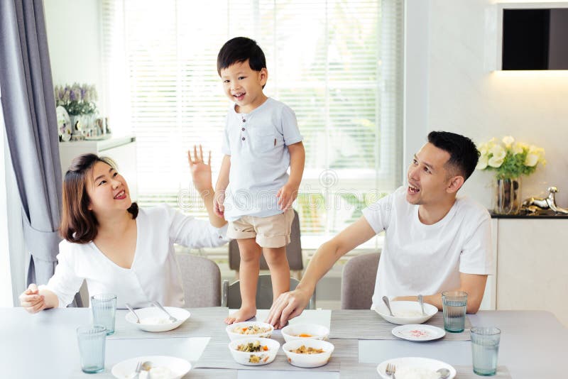 Azjatycka rodzina ogląda ich dzieciaka gdy jest ustalający i dumny w końcu stać na łomota stole