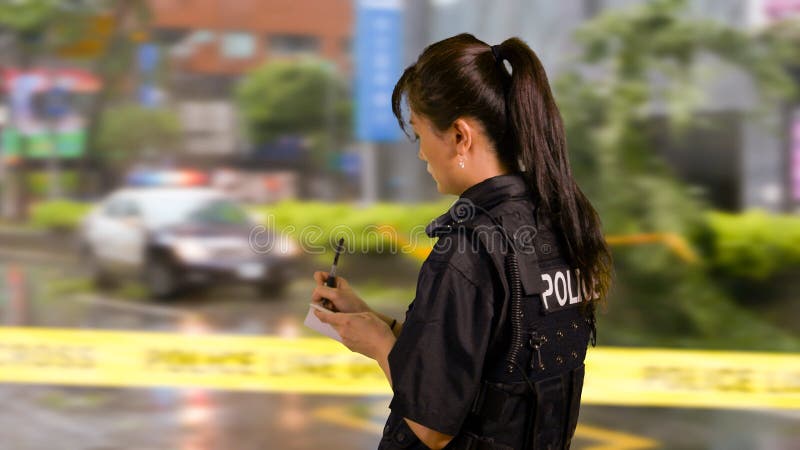 Azjatycki Amerykański kobieta funkcjonariusz policji przy miejscem przestępstwa, boczny widok, zdjęcia royalty free Azjatycki Amerykański kobieta funkcjonariusz policji przy miejscem przestępstwa, boczny widok, zdjęcia royalty free