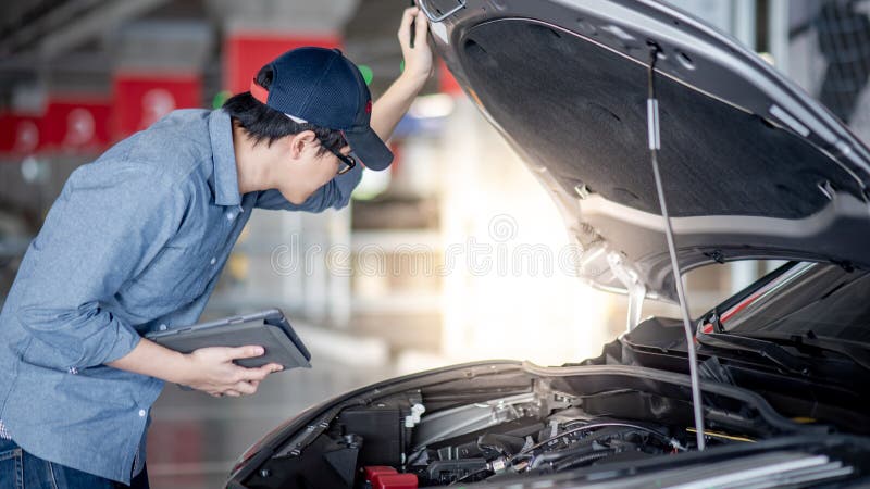 Azjatycki auto mechanik sprawdza samochodow? u?ywa pastylk? zdjęcie stock Azjatycki auto mechanik sprawdza samochodow? u?ywa pastylk? zdjęcie stock