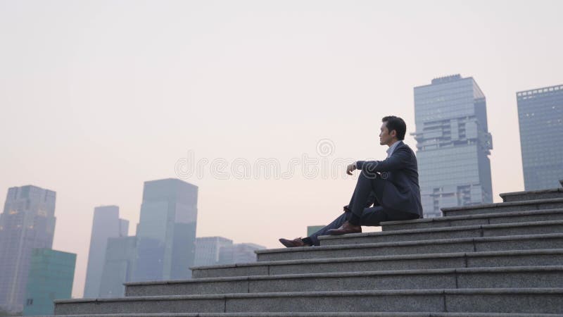 Azjatycki biznesmen siedzący na schodach w centrum miasta