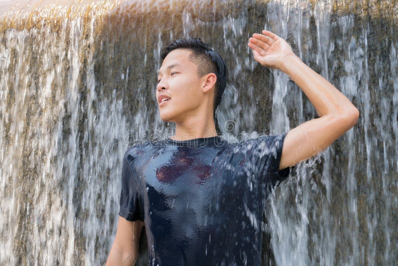 Azjatycki inteligentny młody mężczyzna grający na zasłonie wodospadu pluskał w basenie z uśmiechem i szczęściem w lecie. relaksują