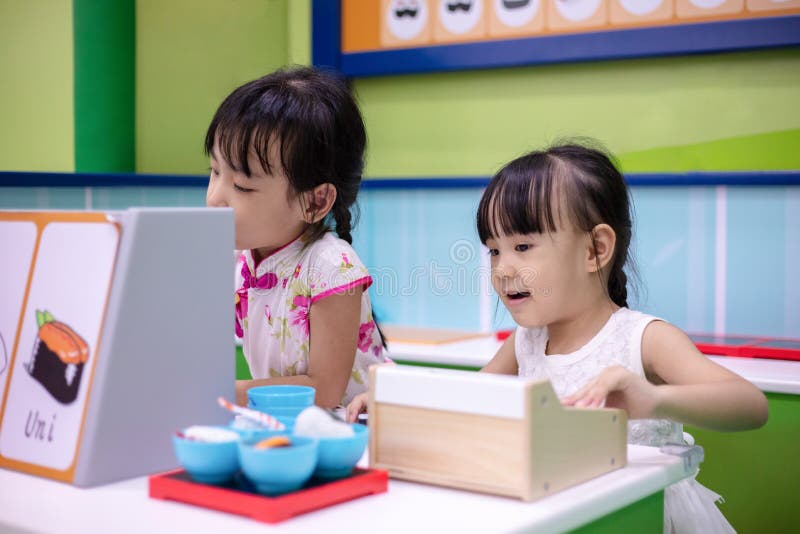 Azjatyckie Chińskie małe siostry bawić się przy suszi sklepem