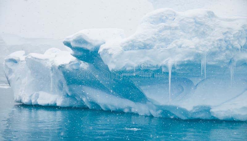 An iceberg reflecting it's azure blues in soft snow fall - Antarctic. An iceberg reflecting it's azure blues in soft snow fall - Antarctic.