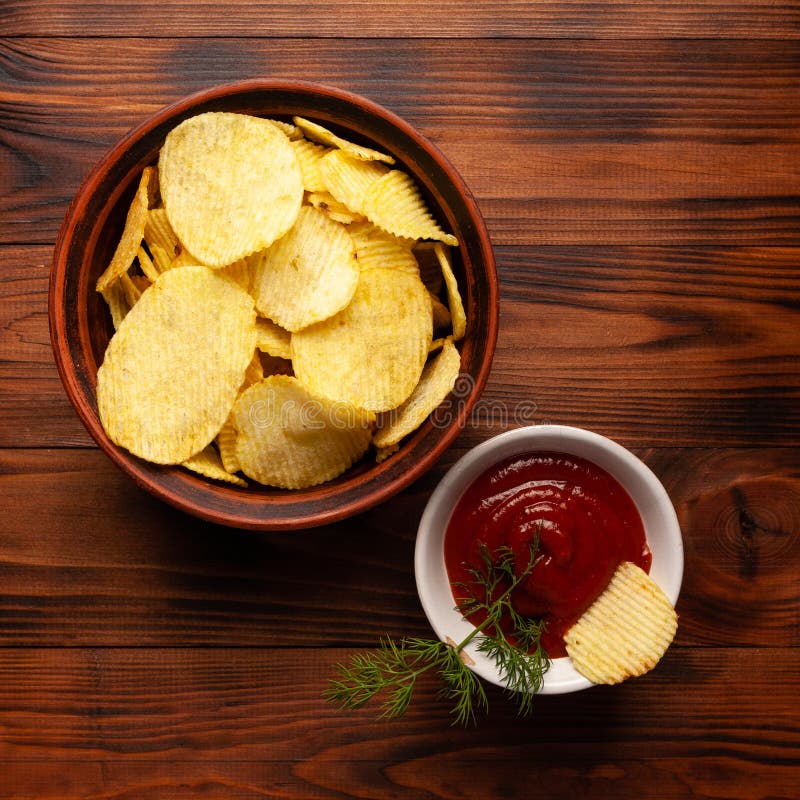 Așchii de cartofi ondulați într-o placă cu ketchup pe o masă din lemn. vedere de sus a gustărilor. chipsuri de cartofi pentru foto royalty free stock photos