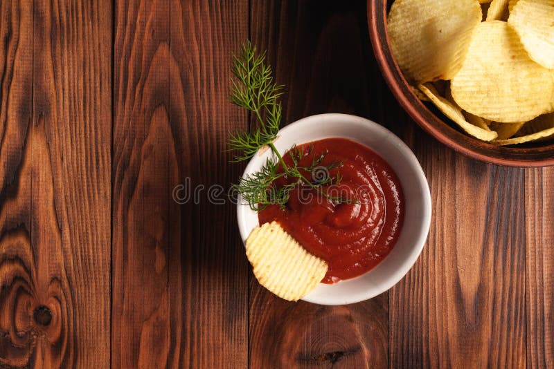 Așchii de cartofi ondulați într-o placă cu ketchup pe o masă din lemn. vedere de sus a gustărilor. chipsuri de cartofi pentru foto royalty free stock photos