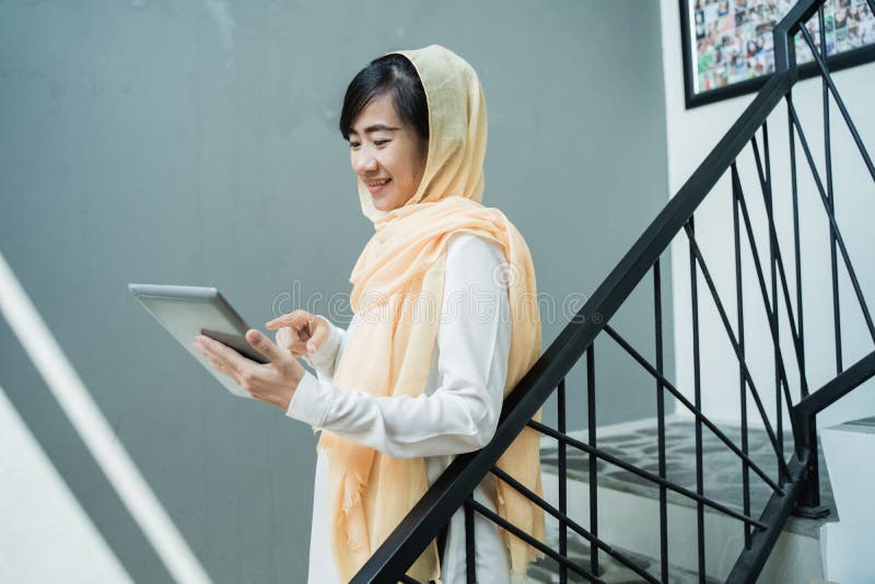 B?rande hijab f?r muslimsk kvinna genom att anv?nda minnestavlaPC royaltyfria bilder B?rande hijab f?r muslimsk kvinna genom att anv?nda minnestavlaPC royaltyfria bilder