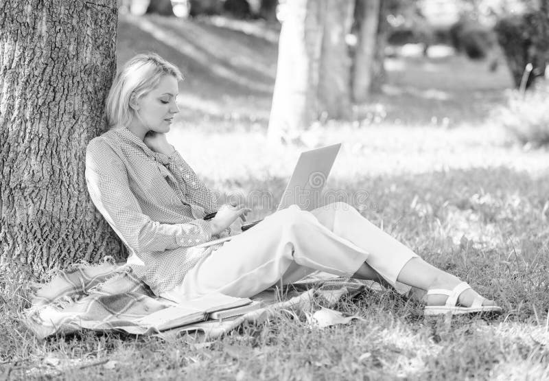 Natural environment office. Work outdoors benefits. Woman with laptop computer work outdoors lean on tree trunk. Education technology and internet concept. Girl work with laptop in park sit on grass. Natural environment office. Work outdoors benefits. Woman with laptop computer work outdoors lean on tree trunk. Education technology and internet concept. Girl work with laptop in park sit on grass.