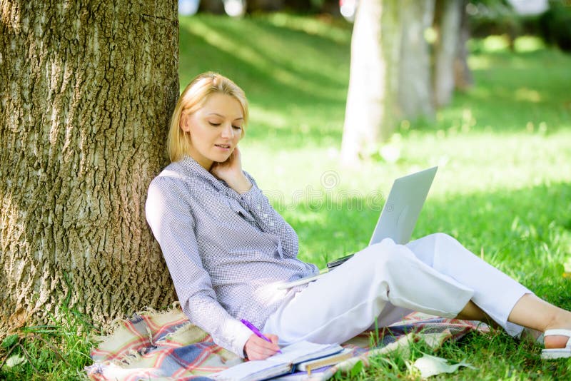 Natural environment office. Work outdoors benefits. Woman with laptop computer work outdoors lean on tree trunk. Girl work with laptop in park sit on grass. Education technology and internet concept. Natural environment office. Work outdoors benefits. Woman with laptop computer work outdoors lean on tree trunk. Girl work with laptop in park sit on grass. Education technology and internet concept.