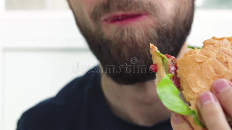 Baardman eet heerlijk hamburger