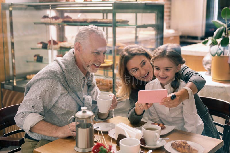 Babcia trzyma jej różowego smartphone pokazuje fotografie wnuczka fotografia stock Babcia trzyma jej różowego smartphone pokazuje fotografie wnuczka fotografia stock