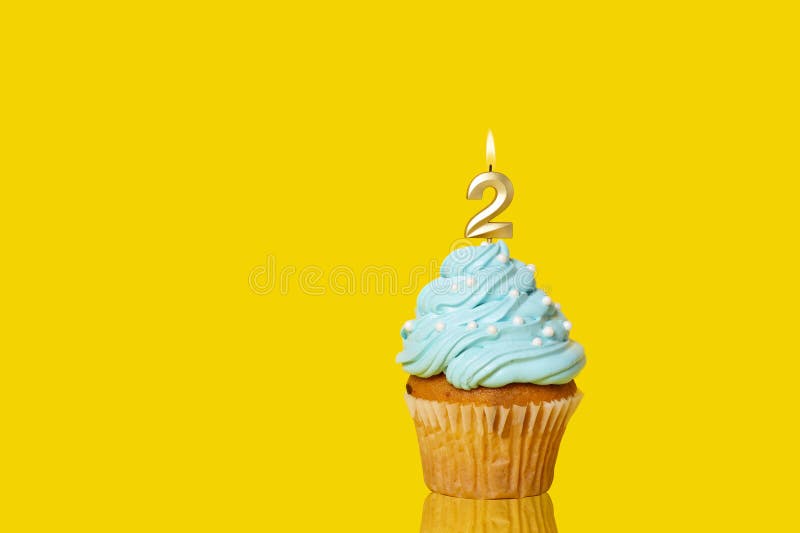 Birthday Cupcake With Candle Number 2 Lit - Photo On Yellow Background. Birthday Cupcake With Candle Number 2 Lit - Photo On Yellow Background