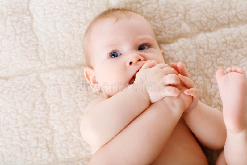 A Naked Caucasian Eightmonthold Baby Sits On A Bed Against 