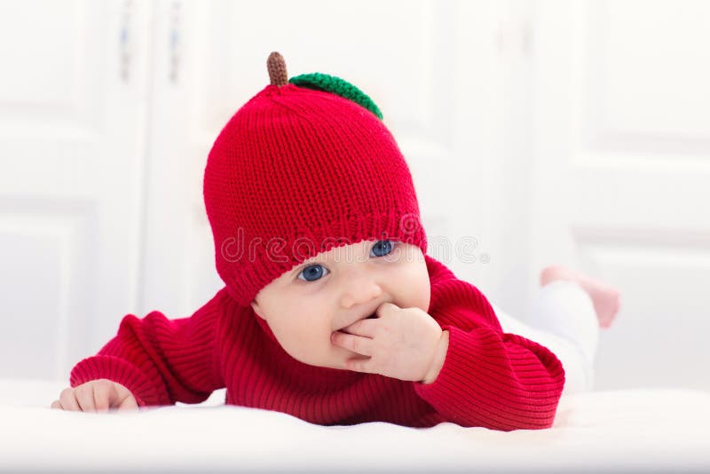 Baby in apple hat. Kid on bed. Child at home royalty free stock images Baby in apple hat. Kid on bed. Child at home royalty free stock images