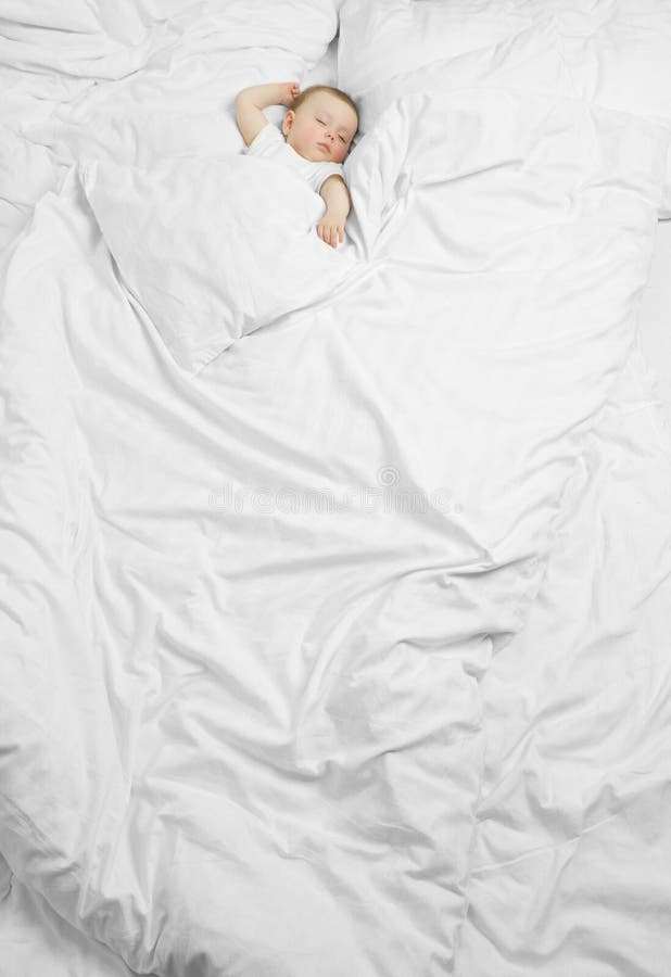 Ein süßes baby schlafen auf einem riesigen Bett mit weißen Laken.