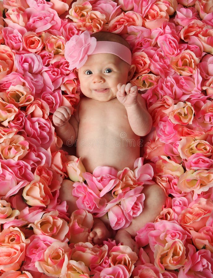 Adorabile bambino sorridente ragazza che giace in un letto di rose rosa.