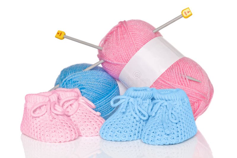 Knitted baby booties with blue and pink wool plus knitting needles, isolated on a white background. Knitted baby booties with blue and pink wool plus knitting needles, isolated on a white background.