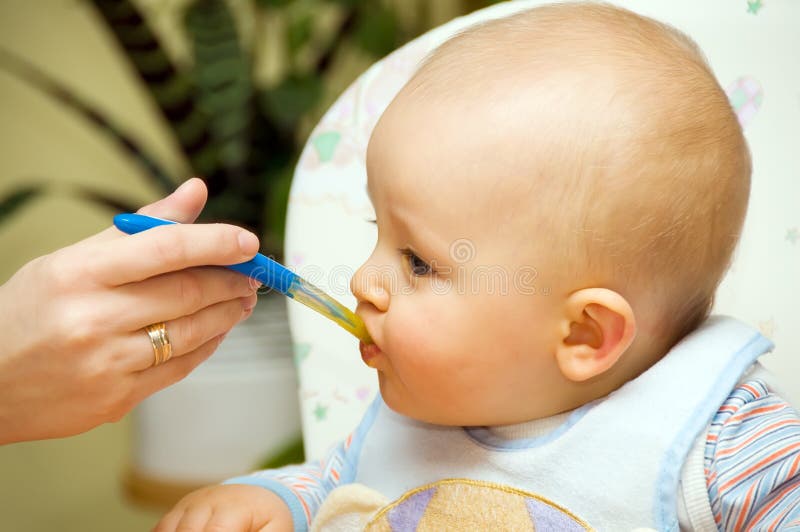 Bambino mangia un pasto con un cucchiaio.