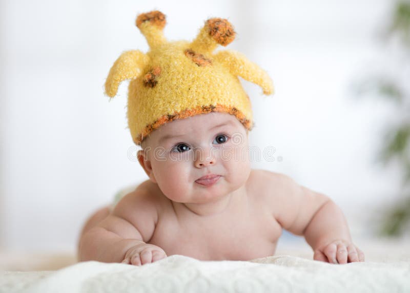 Download Baby Boy In A Funny Giraffe Hat Lying On His Belly In Nursery Stock Image