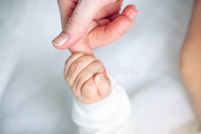 Baby boy holding mother's hand, squeezes the fingers. Concept of empathy, trust, care and tenderness of motherhood