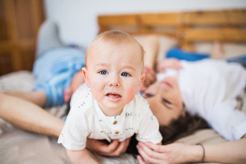 A Baby Boy at Home on Bed with Unrecognizable Parents. Stock Photo