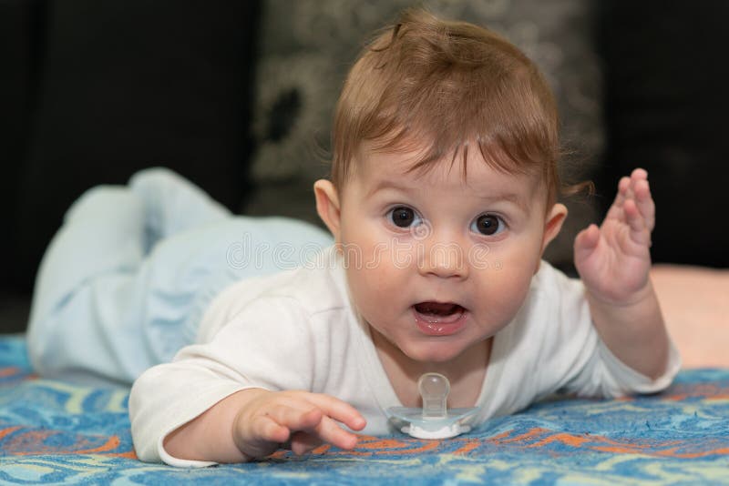 Baby Boy is Lying on Tummy. the Baby Boy Poses and Plays with a Pacifier. Stock Image Image of