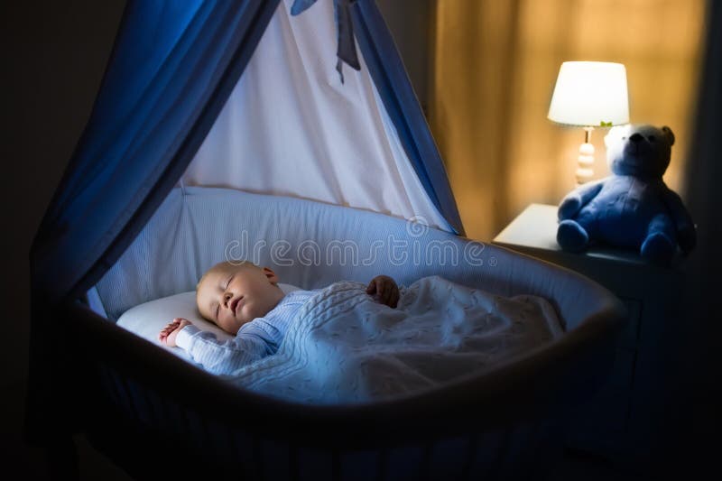 Adorabile bambino che dormiva in blu culla con baldacchino durante la notte.