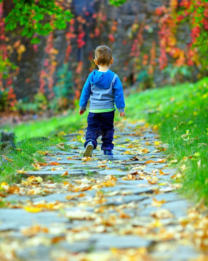 Baby boy walking away the autumn path