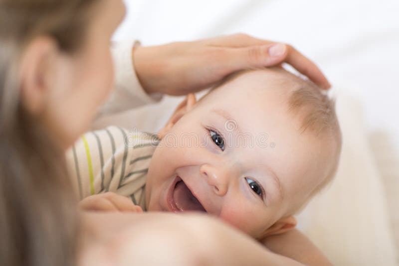 Baby breastfeeding. Mother holding her newborn child. Little kid laughing and looking at camera.