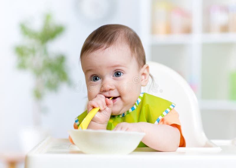 Baby child sitting in chair with a spoon stock photography Baby child sitting in chair with a spoon stock photography