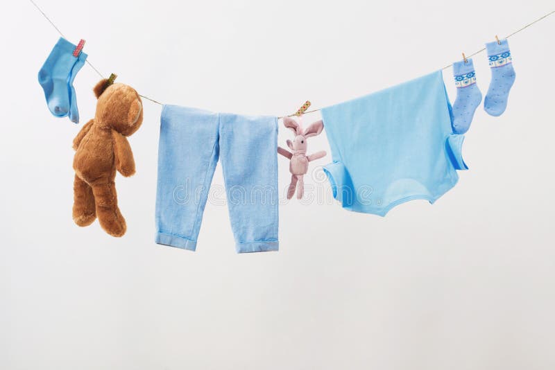 Baby clothes hanging on rope on white background stock photos Baby clothes hanging on rope on white background stock photos