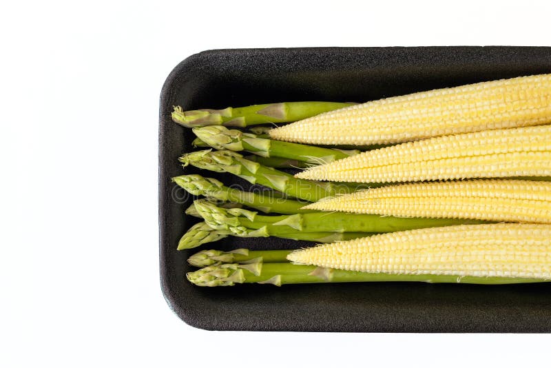 Baby Corn and Asparagus in a Black Packing Tray Isolated on White Stock