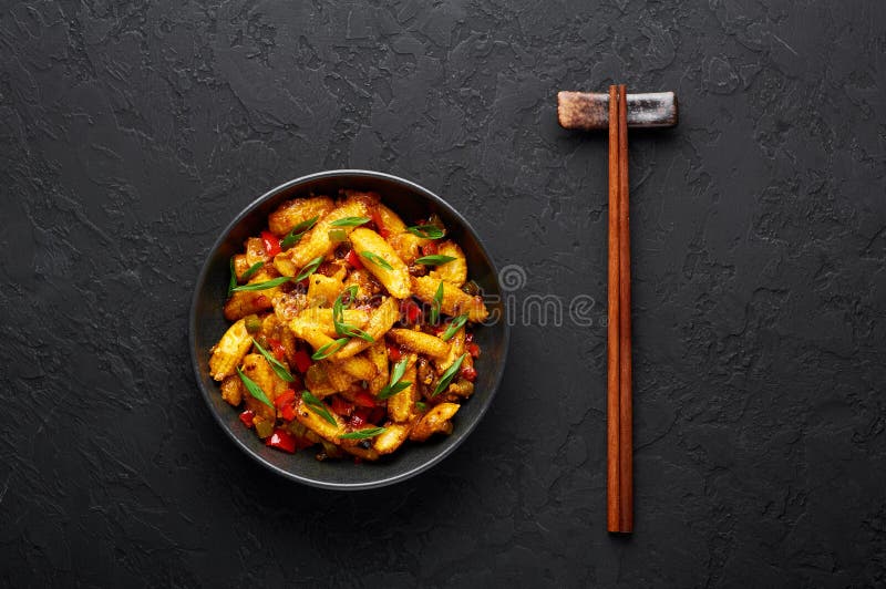 Baby Corn Manchurian, torr ser ut som Schezwan Baby Corn i svart skål med mörk bakgrund
