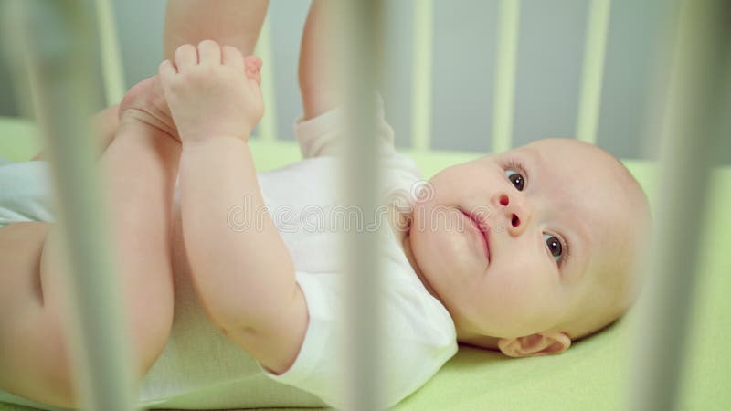 Baby die in een voederbak en het spelen liggen stock afbeelding Baby die in een voederbak en het spelen liggen stock afbeelding