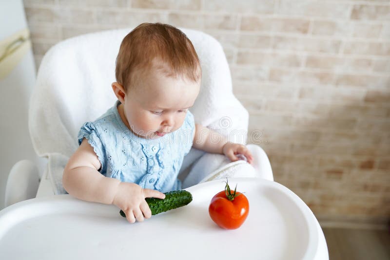 Baby die groenten eten de groene komkommer in meisje dient zonnige keuken in Gezonde voeding voor jonge geitjes Snack of ontbijt royalty-vrije stock afbeelding Baby die groenten eten de groene komkommer in meisje dient zonnige keuken in Gezonde voeding voor jonge geitjes Snack of ontbijt royalty-vrije stock afbeelding