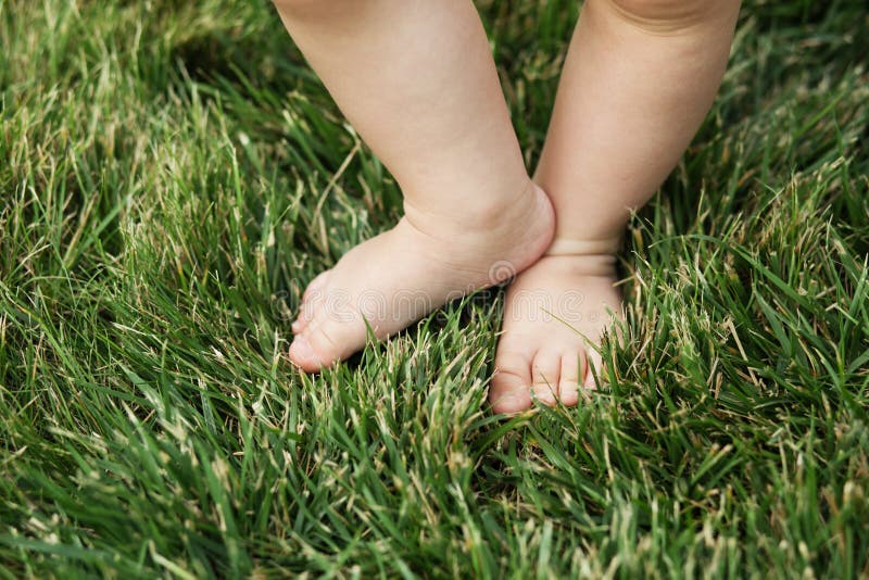 Baby die zich blootvoets op het gras bevinden stock foto's Baby die zich blootvoets op het gras bevinden stock foto's