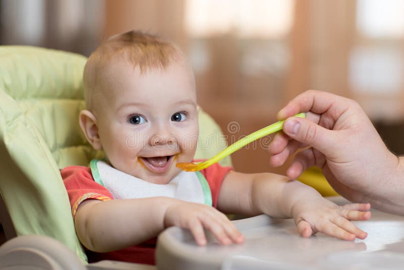 Baby eating food with father help