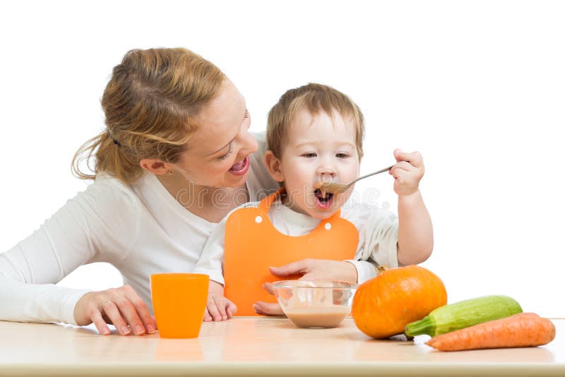 Baby eating vegetables by spoon himself and mother